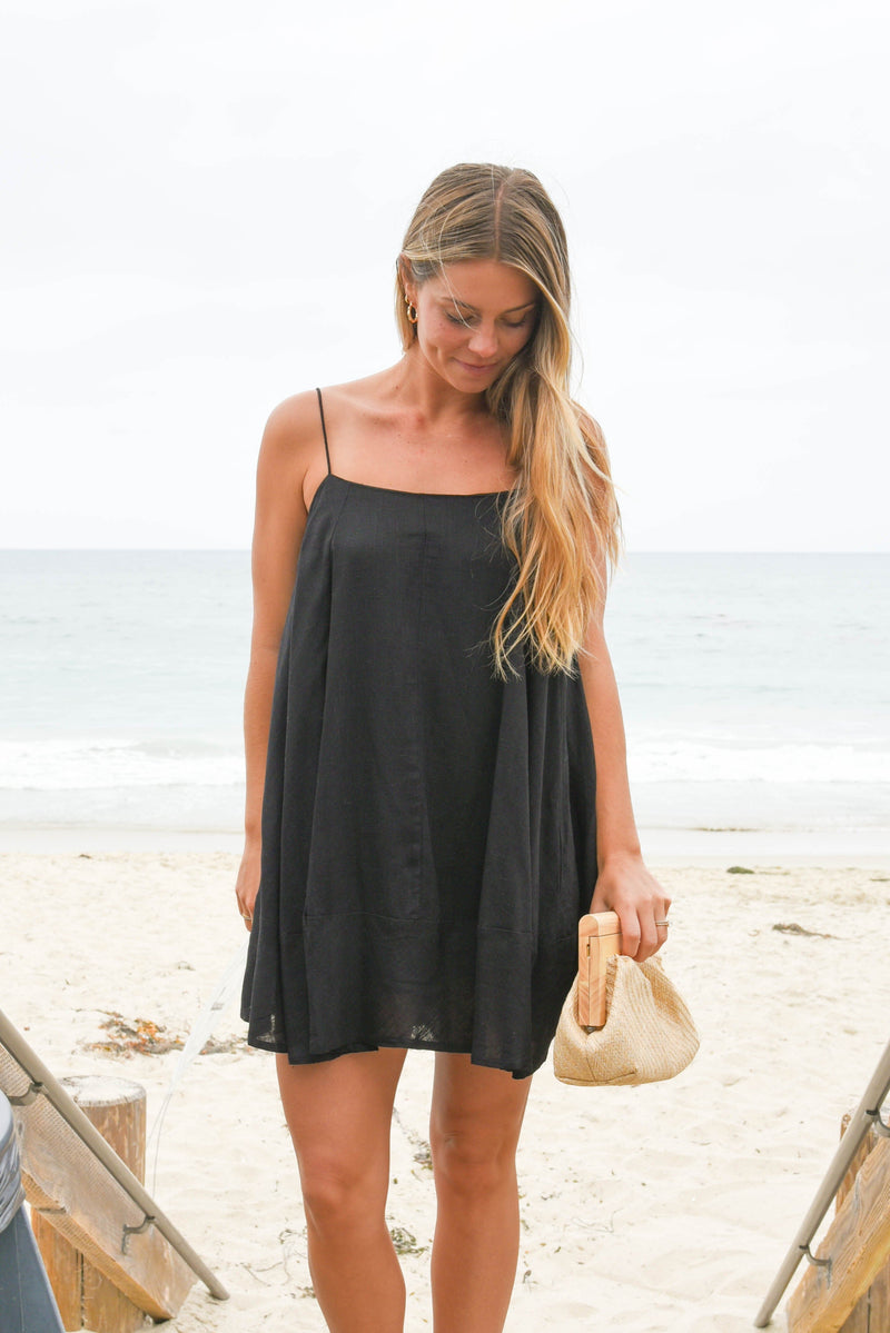 Woman in a black dress standing on a beach